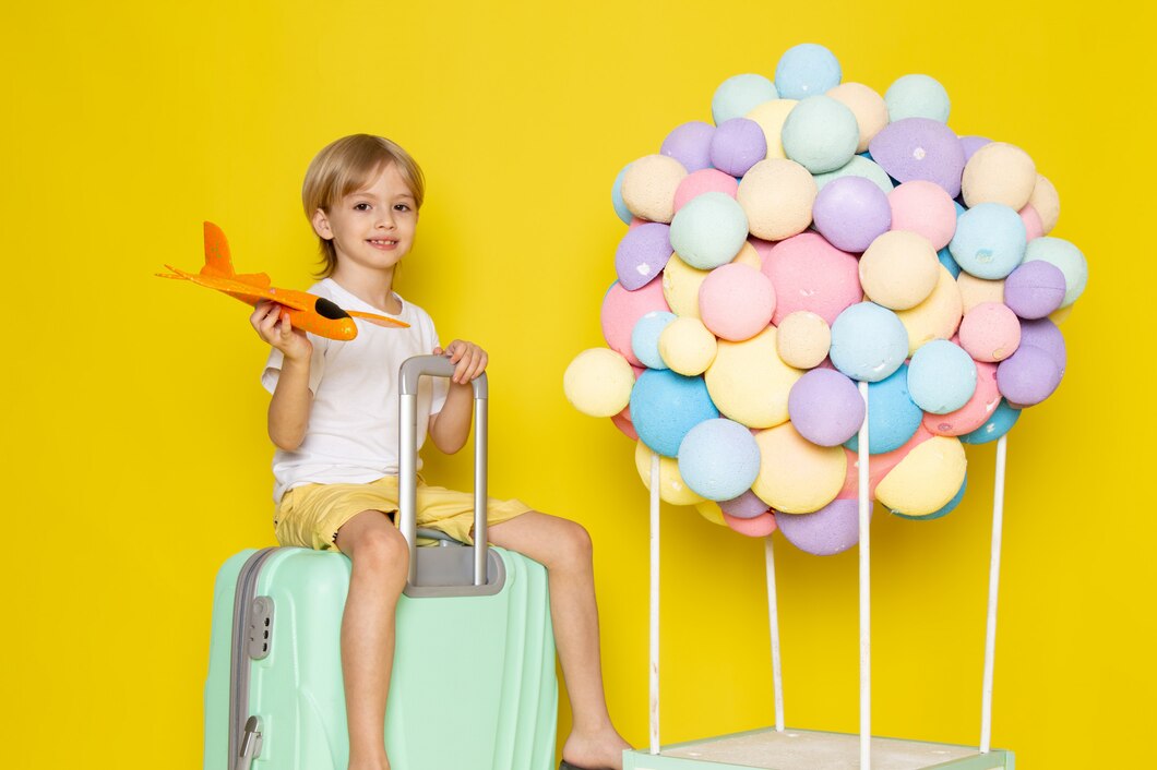 Front View Smiling Blonde Boy Playing With Orange Toy Plane Along With Colorful Air Balloons Yellow Desk | Play and Dream Toys UAE